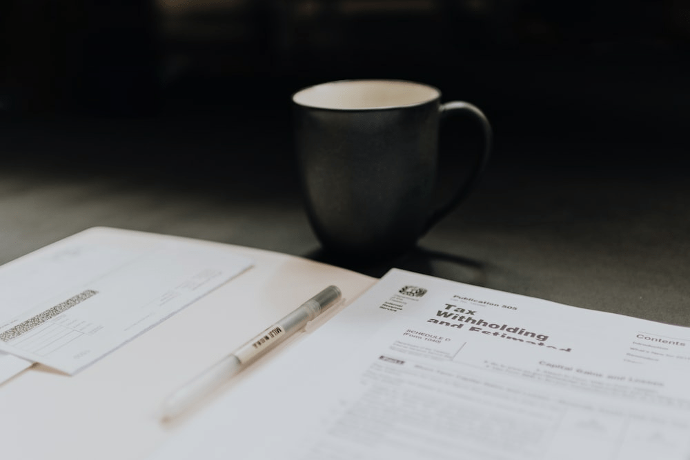 Coffee mug near open folder with tax withholding paper