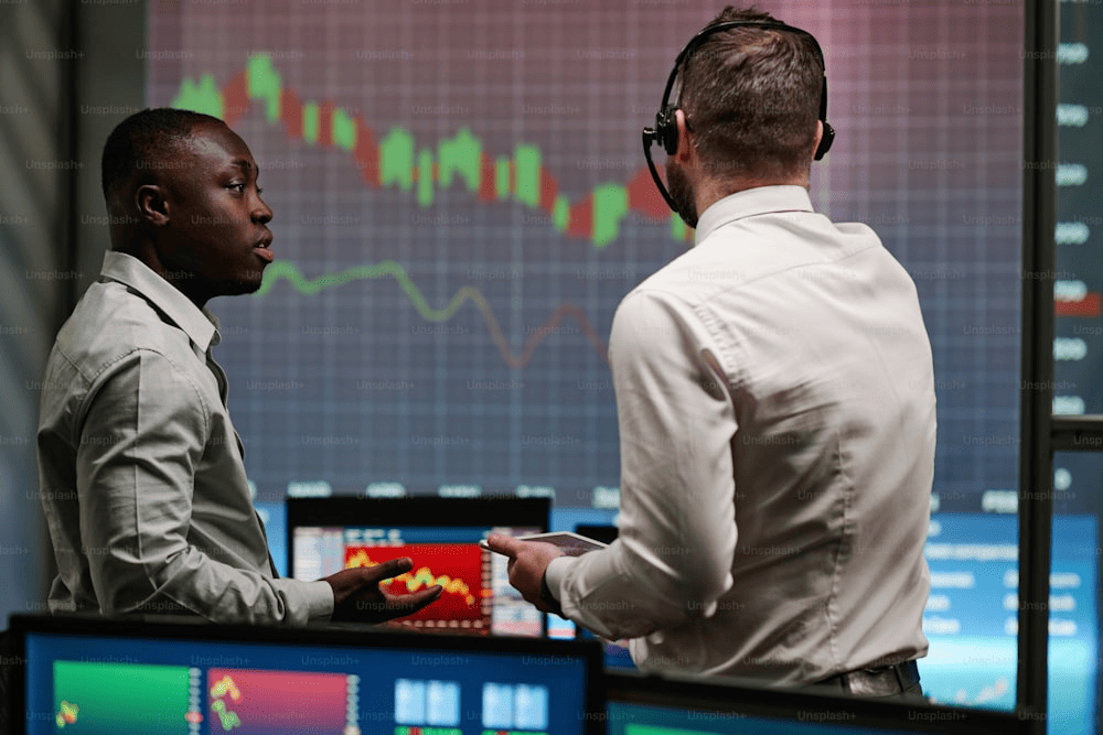 Caucasian man and his African American colleague working in stock trading company discussing currency fall