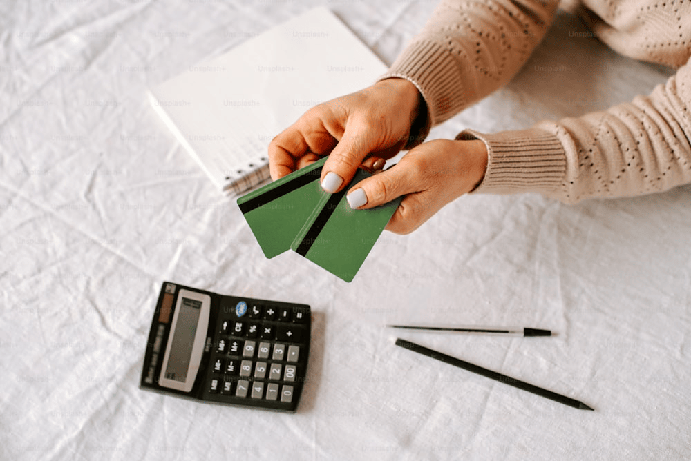 a person holding a piece of paper next to a calculator